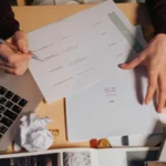 Person-reviewing-and-marking-documents-at-a-desk-1024x576